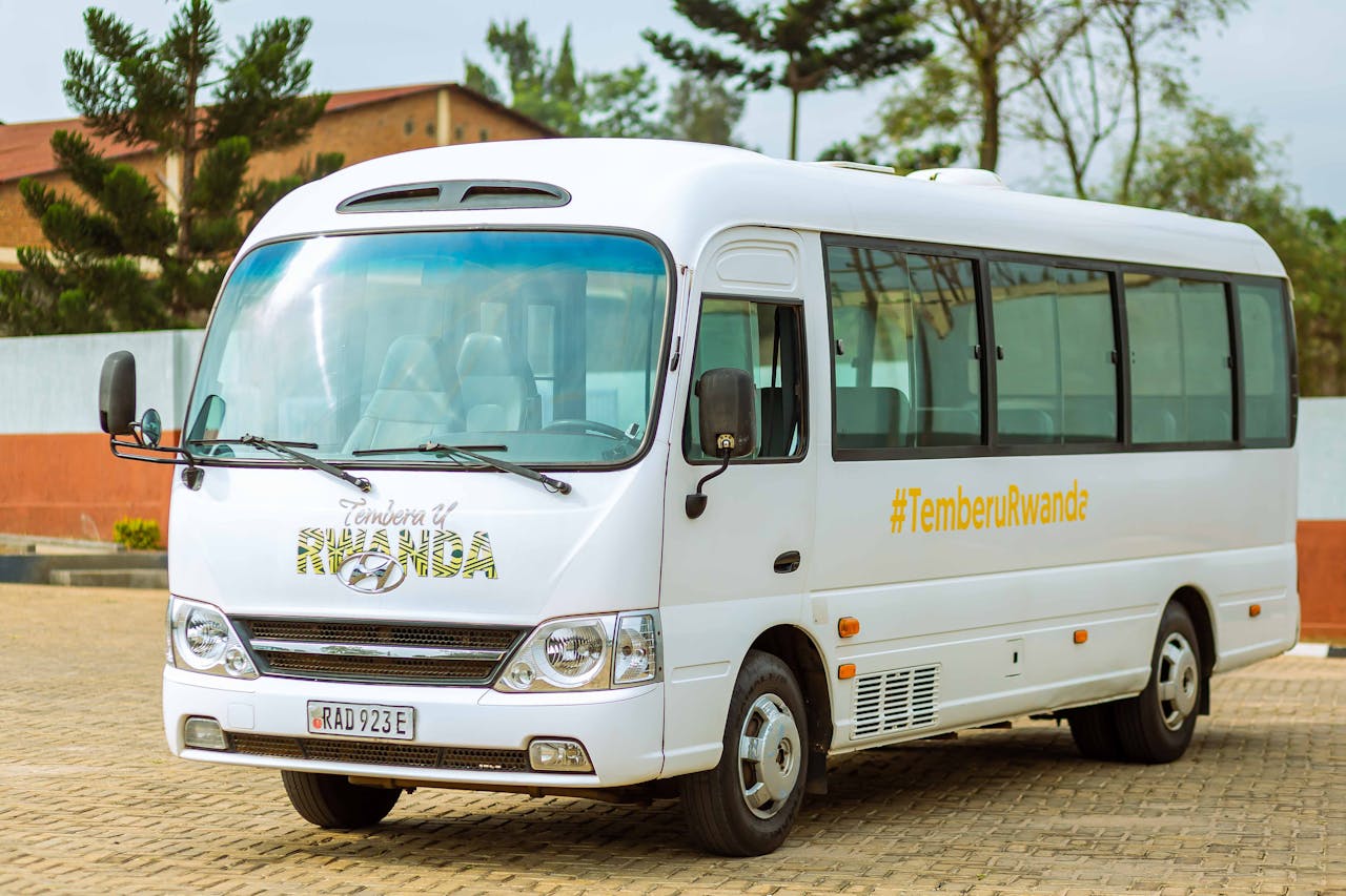 A white tour bus promoting TemberuRwanda, parked outdoors on a sunny day.